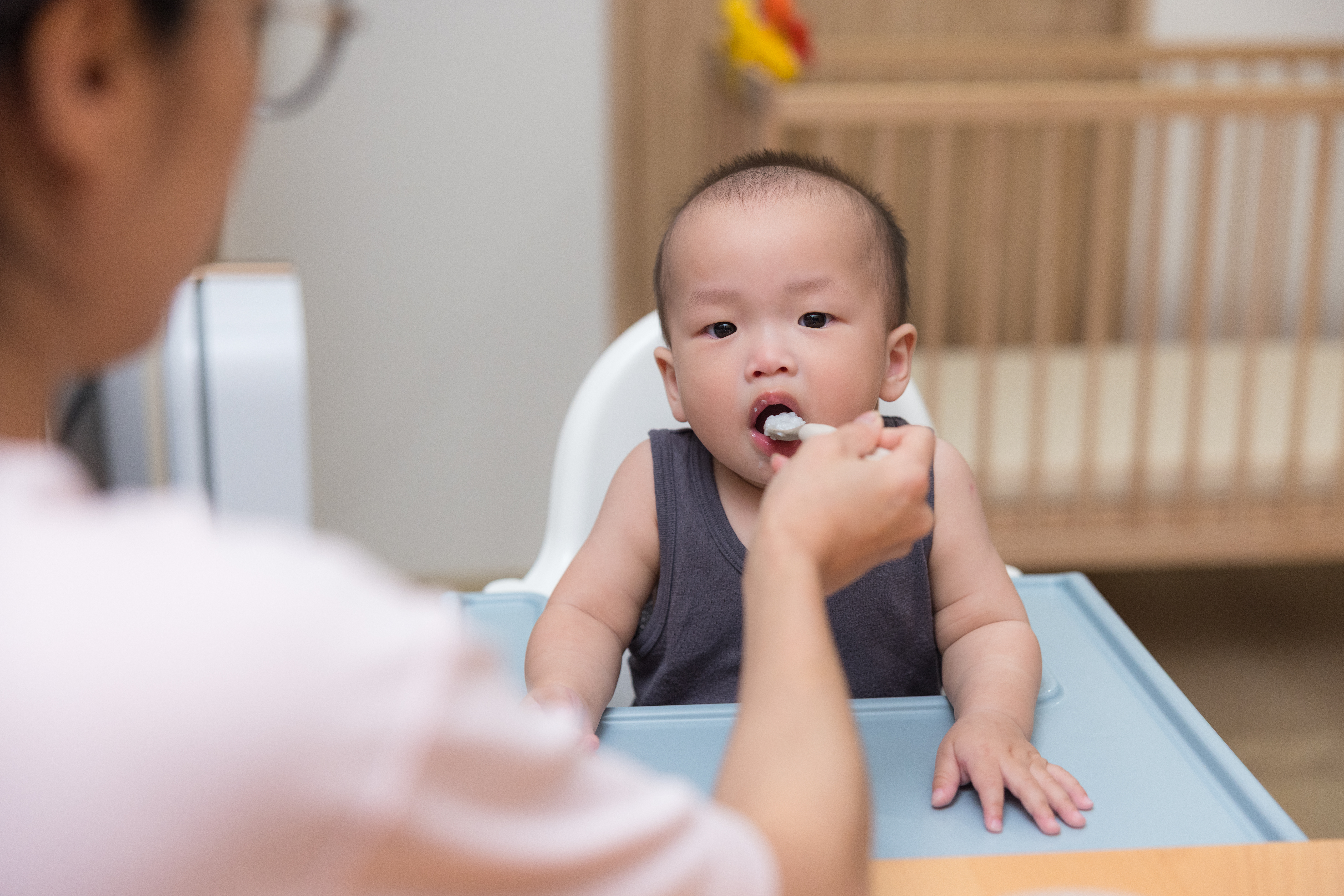parent feeding a young child in a high chair