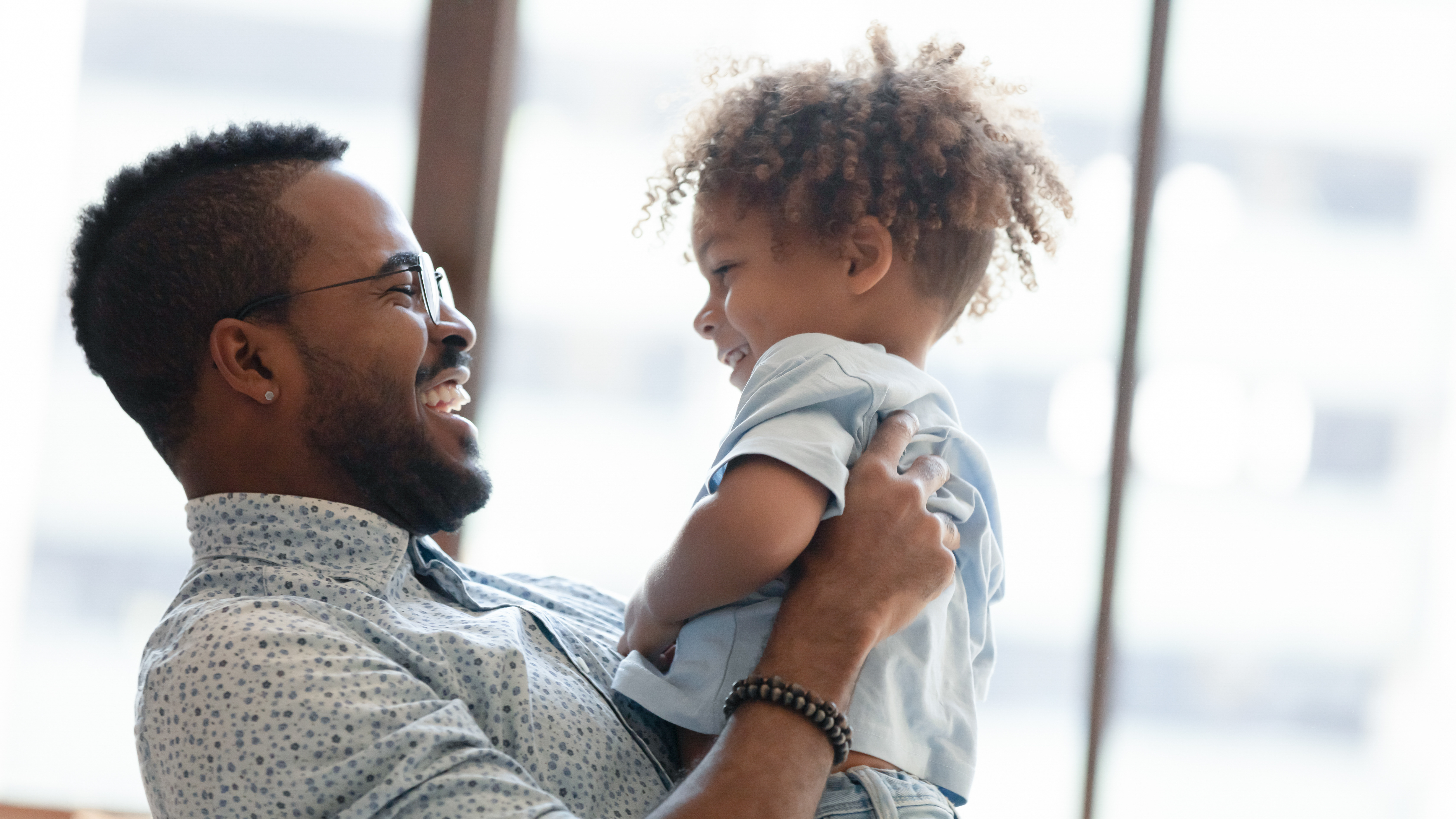 happy parent holding up a smiling young child
